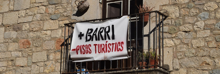 Pancarta de la plataforma "Més barri, menys pisos turístics" en un balcó de Girona